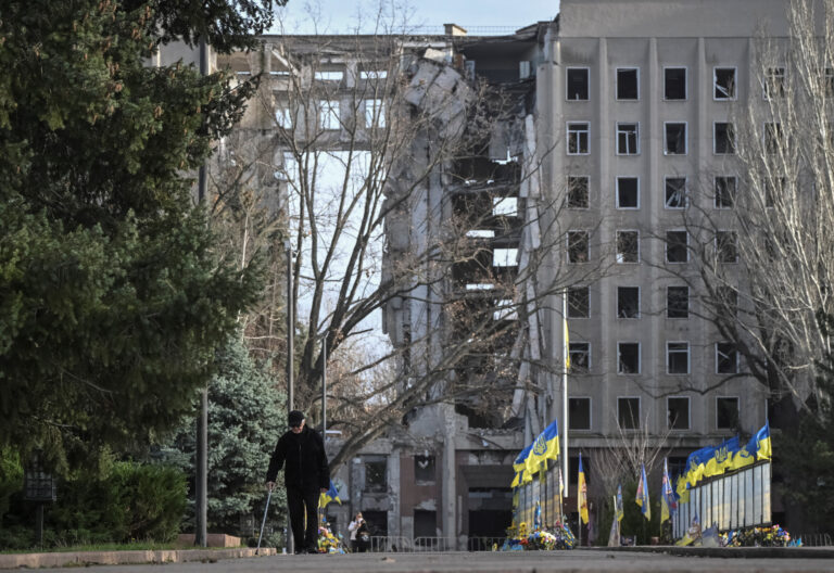 A man walks next to a damaged building in Mykolaiv